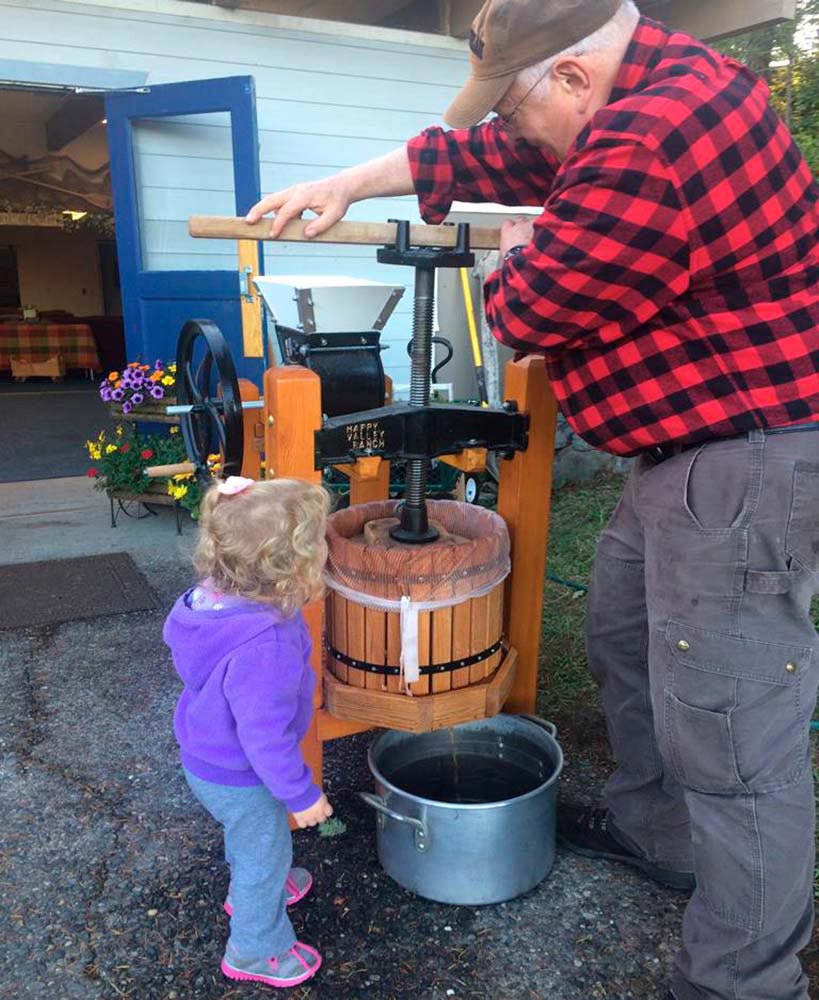 Director and Granddaughter Making Apple Cider